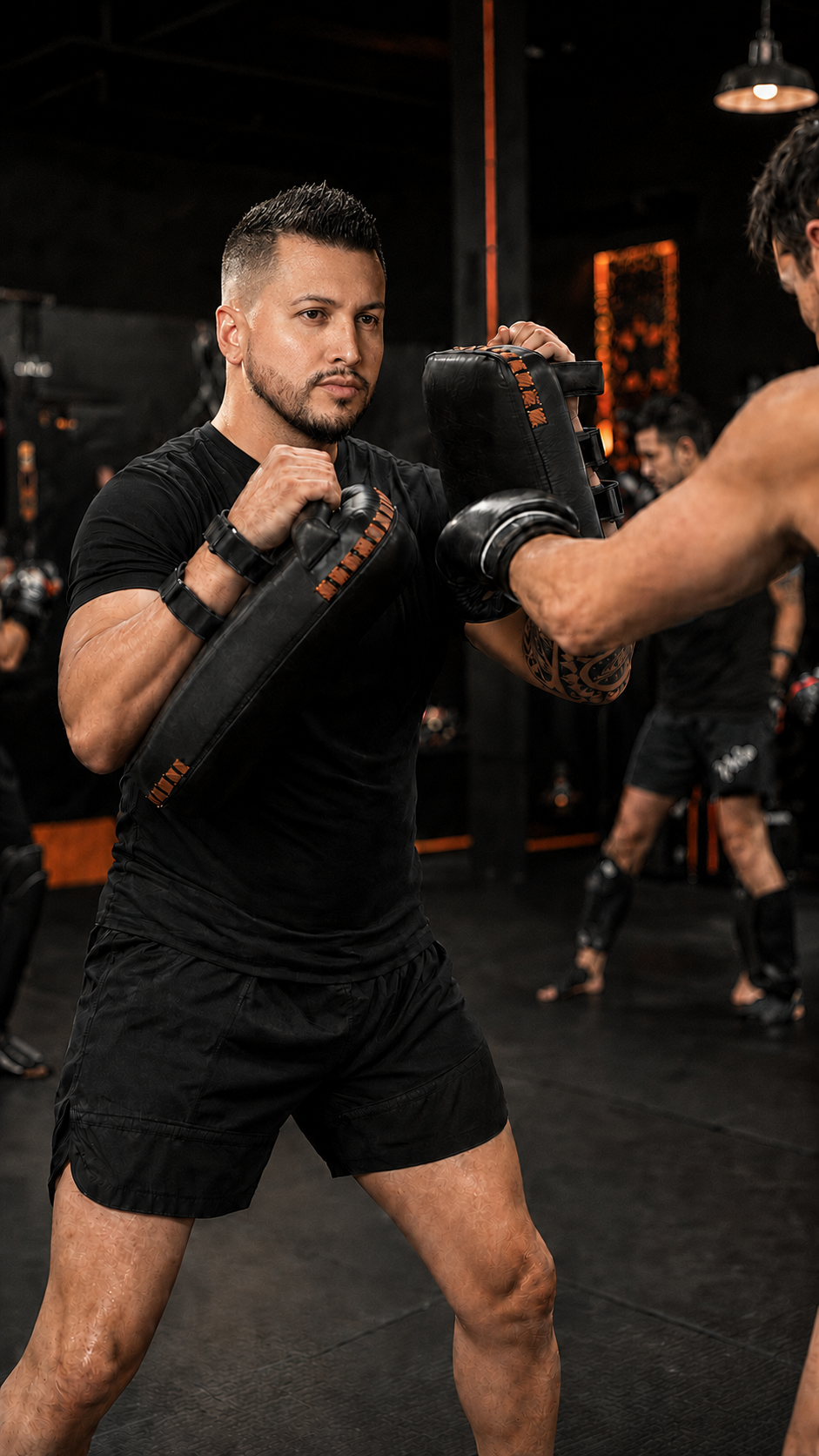 Kru JT Garcia holding pads for an adult Muay Thai student during class